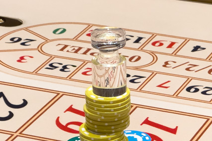 Mark winning numbers on roulette tables with dolly. Casino dealer places win marker on roulette layout to display players the winning number.