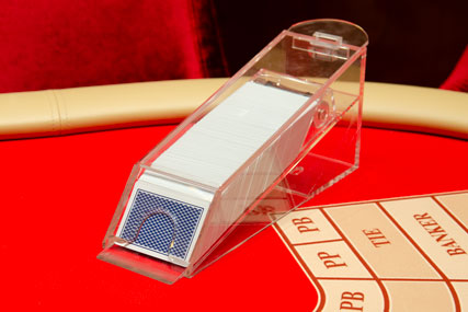 Fully transparent card dealing shoe with capacity of 8 playing card decks reassures Baccarat players of fair gameplay on casino floor.